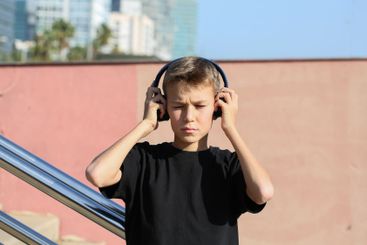 Handsome teenager standing with skateboard and listening...