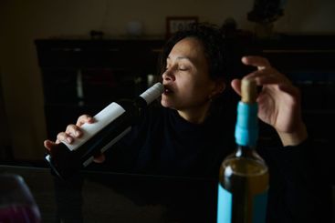 A woman enjoying wine while seated in a dark indoor setting