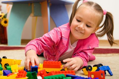 Little girl is playing with toys in preschool