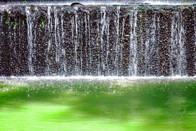 Waterfall built green water on rock wall inside mountain...