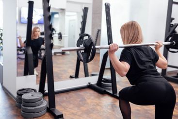 Strained pretty sportswoman in black sportswear lifting...