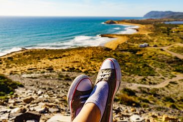 Female feet against coast landscape, Spain.