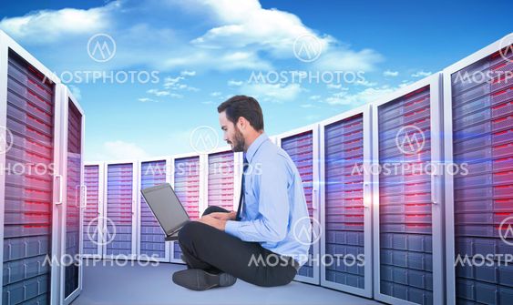 Composite image of businessman sitting on the floor using his laptop