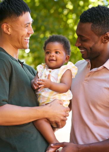 Loving Same Sex Male Couple Or Friends Cuddling Baby...