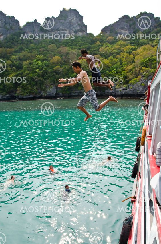 Travellers leap from the deck into the water.