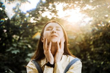 Woman enjoying sunlight with closed eyes in a serene...