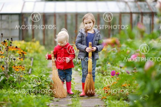Two sisters holding brooms at autumn