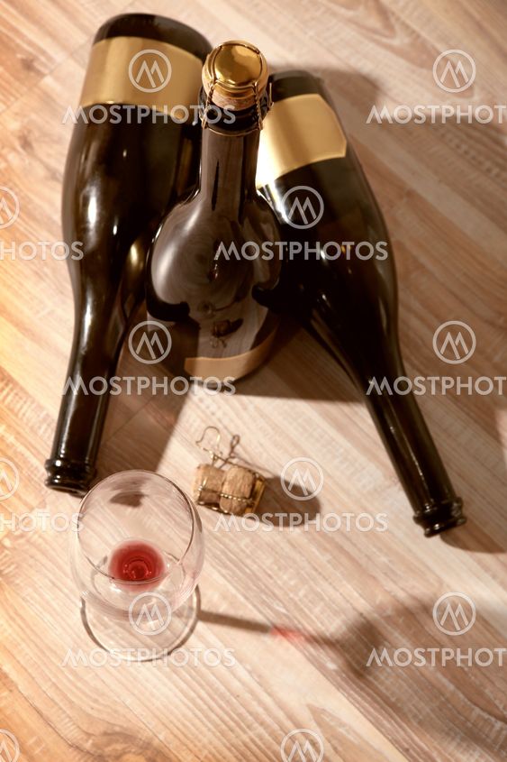 bottles with wine and empty wine glass