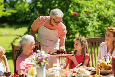 family having dinner or barbecue at summer garden