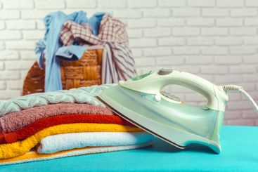 Iron on ironing board on light home interior background