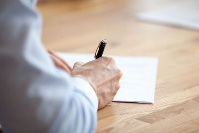 Man hand holding pen, writing notes at meeting close up
