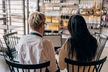 Rear view of female owner and colleague sitting at table...
