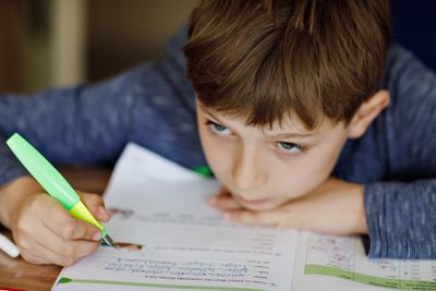 Upset school kid boy making homework during quarantine...