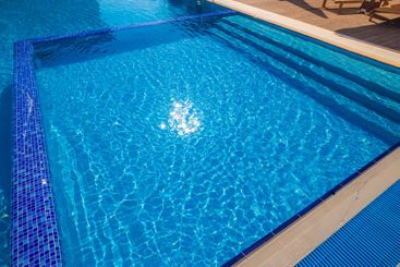 Bright sunlight reflecting on clear blue water in a...