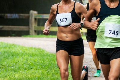 Adults running 5K race on dirt path on hot summer day