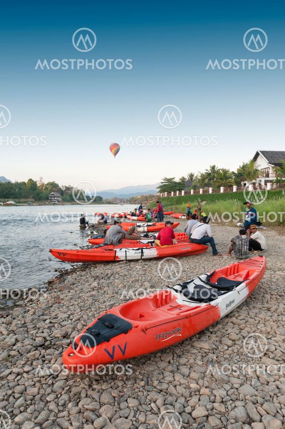 Vang Vieng, Laos - November 2015: Hot air balloons flying over Nam Song River and tourist kayaks in Vang Vieng, popular resort town in Lao PDR