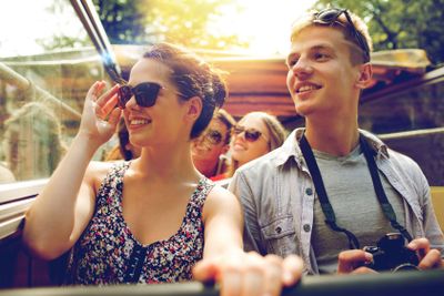 smiling couple with camera traveling by tour bus