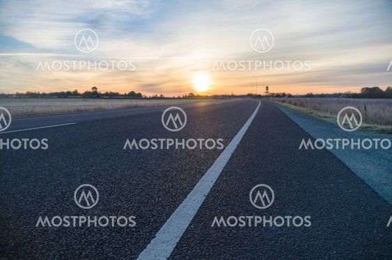 Empty turning asphalt road closeup and sunrise cloudscape on backdrop