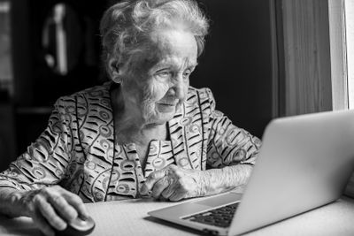 An elderly woman with a laptop. Black-and-white photo.