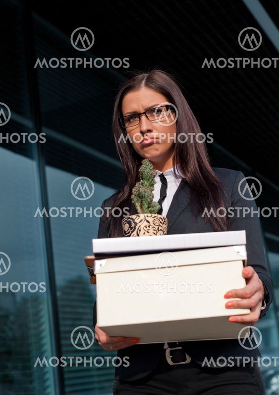Beautiful sad looking businesswoman holding a box of her belongings after being fired