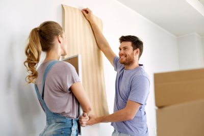 couple with wallpaper repairing apartment or home