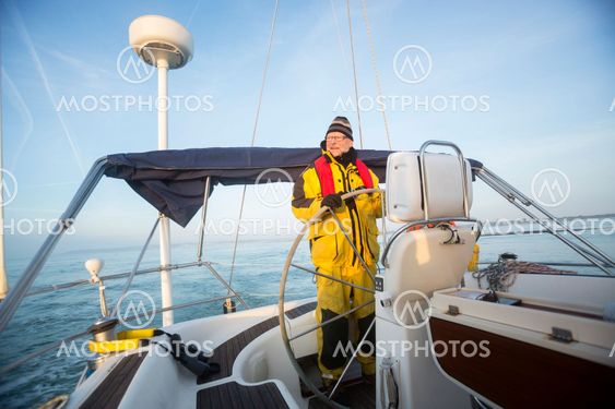 Man Steering Wheel Of Sail Boat In Sea
