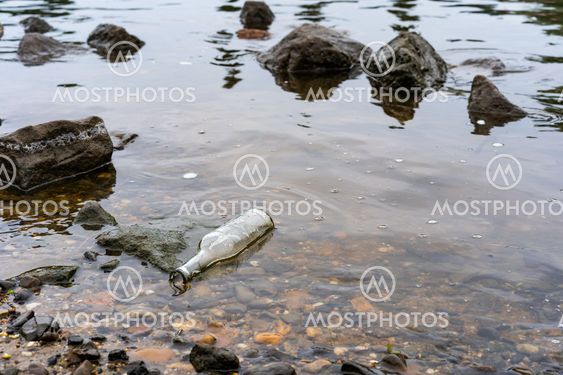 A glass bottle in the river as litter.