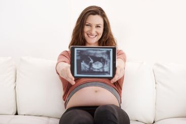Home, woman and smile with pregnancy scan on sofa in...
