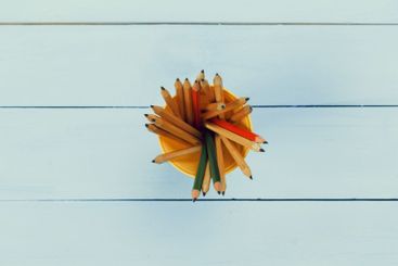 Colorful pencils arranged neatly in a yellow holder on a...