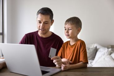 Father and little son buying goods using card and laptop