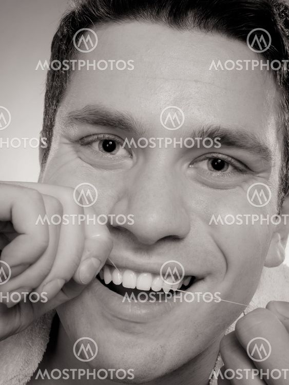 Young man cleaning her white teeth with dental floss