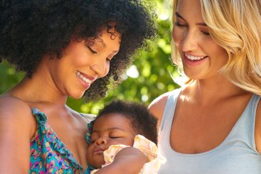 Loving Same Sex Female Couple Or Friends Cuddling Baby...