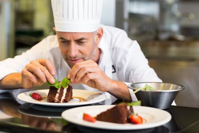 Concentrated male pastry chef decorating dessert in kitchen