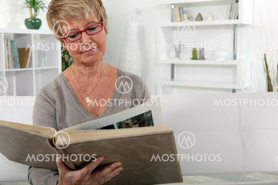 grandmother skimming through family album in lounge
