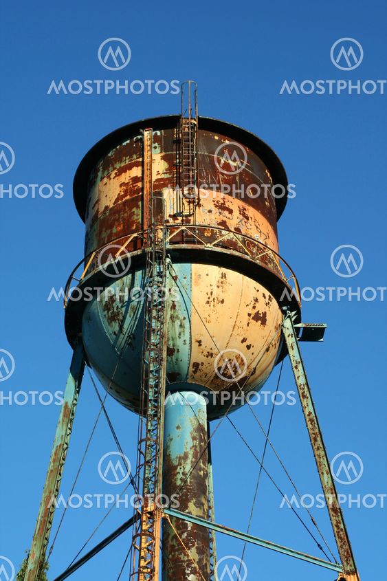 Old rusty watertower against blue sky