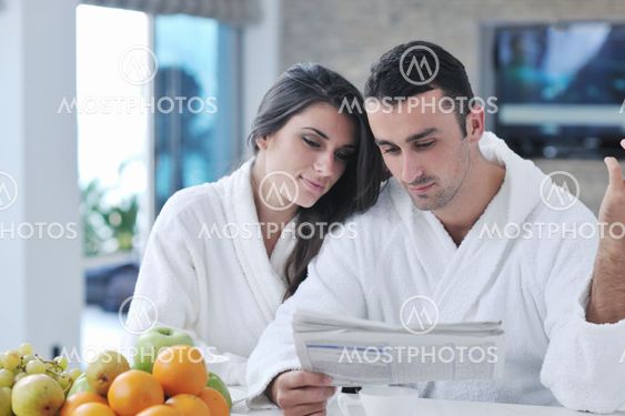 Happy couple reading the newspaper in the kitchen at breakfast
