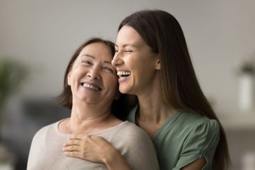 Lovely daughter and her middle-aged mother cuddling indoors