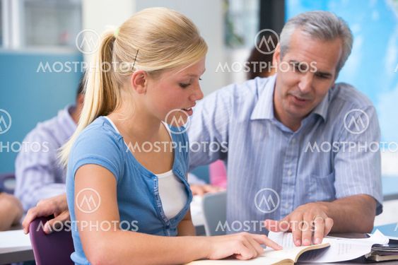 A teacher instructs a schoolgirl in a high school class