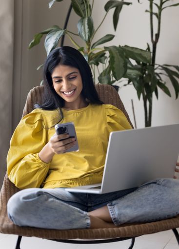 Woman sitting with laptop, distracted from work, using...