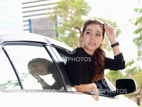 Young pretty Asian girl looking at back of car