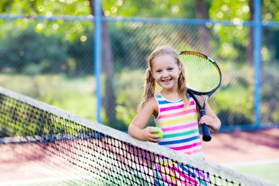 Child playing tennis on outdoor court