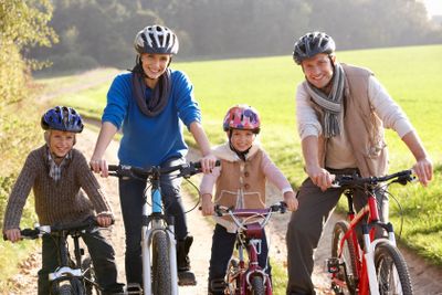 Young family pose with  bikes in park
