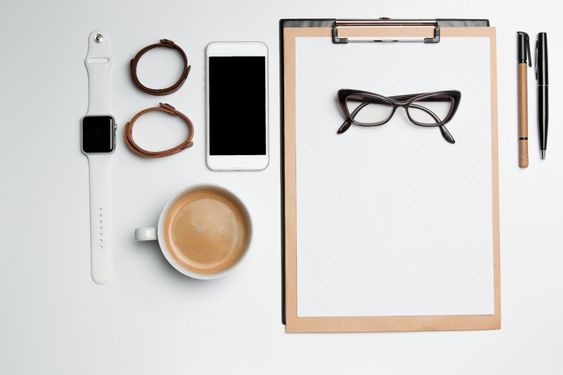 Office desk table with cup, supplies, phone on white
