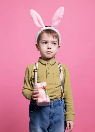 Young happy toddler showing a decorated fluffy rabbit in...