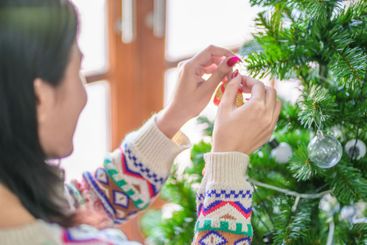 Happy asian woman Decorating Christmas tree for xmas...