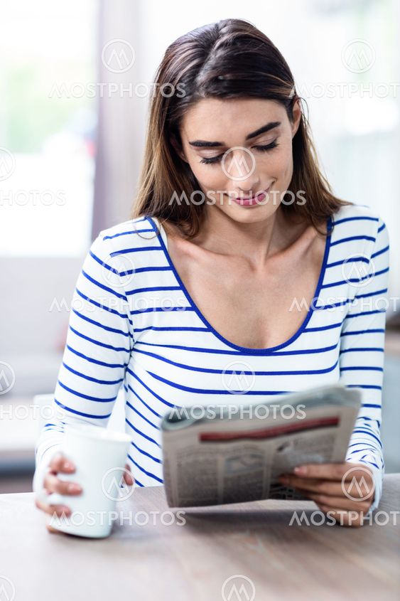 Happy young woman reading newspaper