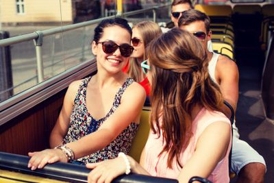 group of smiling friends traveling by tour bus