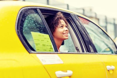 happy african american woman driving in taxi