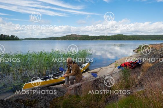 Man resting on the riverside after active paddling on...