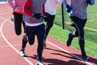 Four runners training on a track in the winter